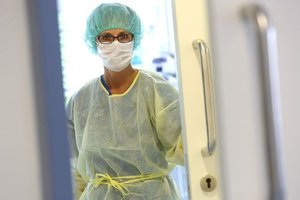 Krankenhaus-Mitarbeiterin mit Schutzkleidung und MNS