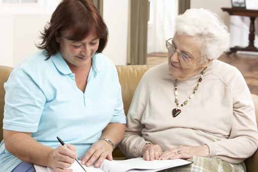 Frau hilft älterer Frau beim Ausfüllen eines Formulars